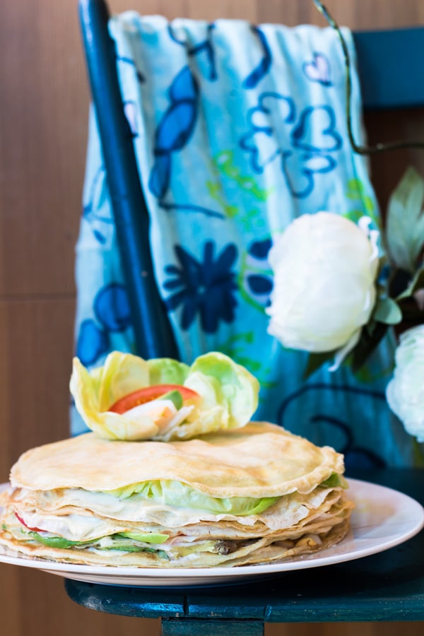 My Mum's Crepe Cake on a plate on a blue table with a blue floral scarf in the background.