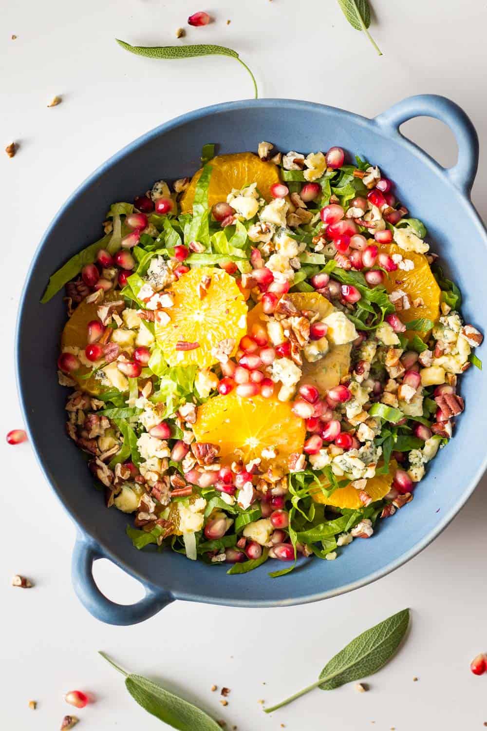 Finished whole bowl of winter salad with romaine lettuce, orange slices, chopped pecans, blue cheese and pomegranate seeds.