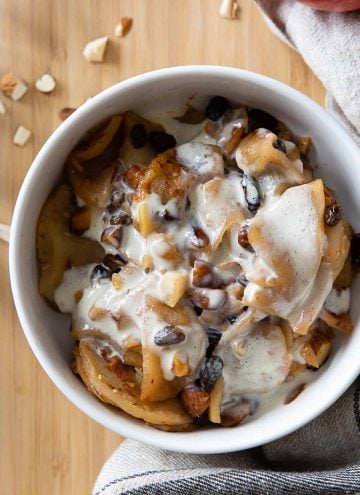 Sliced Baked Apples in a white bowl with custard on top.