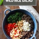 Unmixed wild rice salad ingredients in a blue salad bowl with text overlay of title for Pinterest.