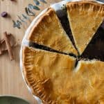 Tourtière meat pie cut up into pieces in baking dish.