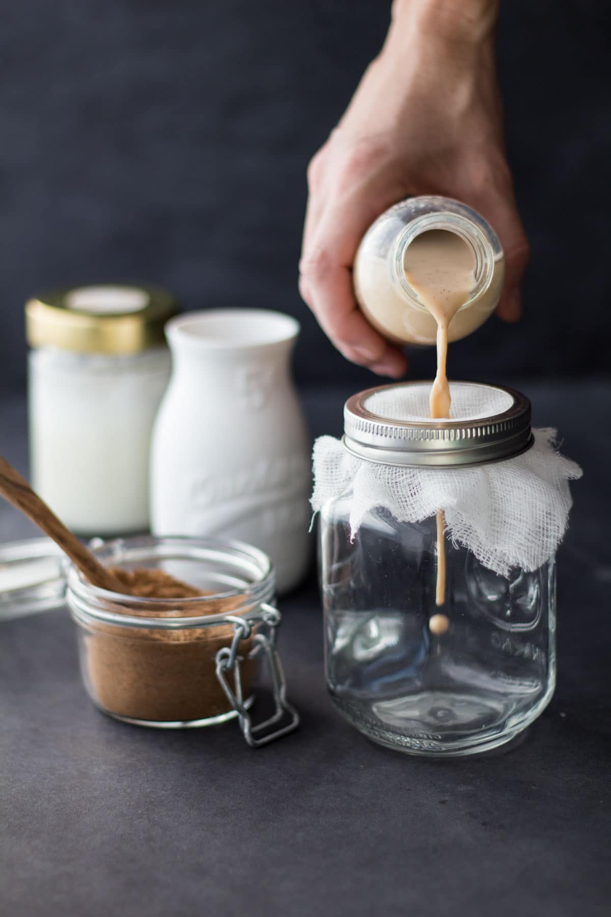 Straining hot black tea infused with chai spice mix to make a homemade chai latte.