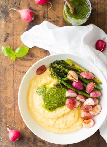 Top view of Creamy Parmesan Polenta with Grilled Vegetables and 5-Minute Basil Pistachio Pesto, an open jar of pesto sauce, and a white napkin.