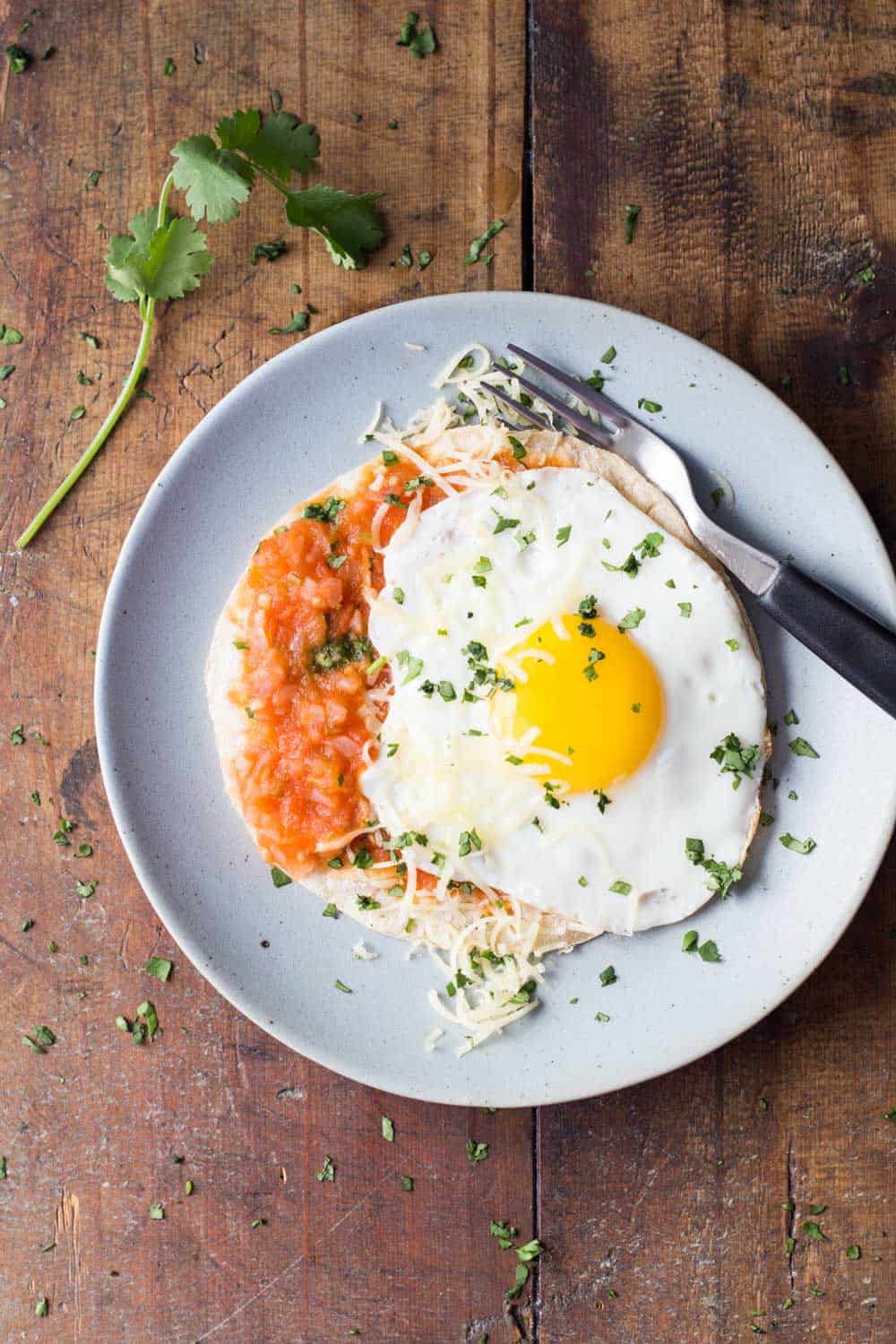 Top view of Huevo Ranchero on a plate with a fork, on a wooden board.