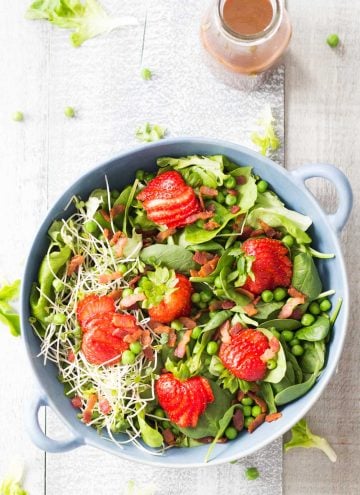 Top view of Strawberry Bacon Spring Salad and a jar of Maple Mustard Balsamic Dressing.