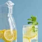 Pitcher with water and lemon slices and glass with ice and lemon slices
