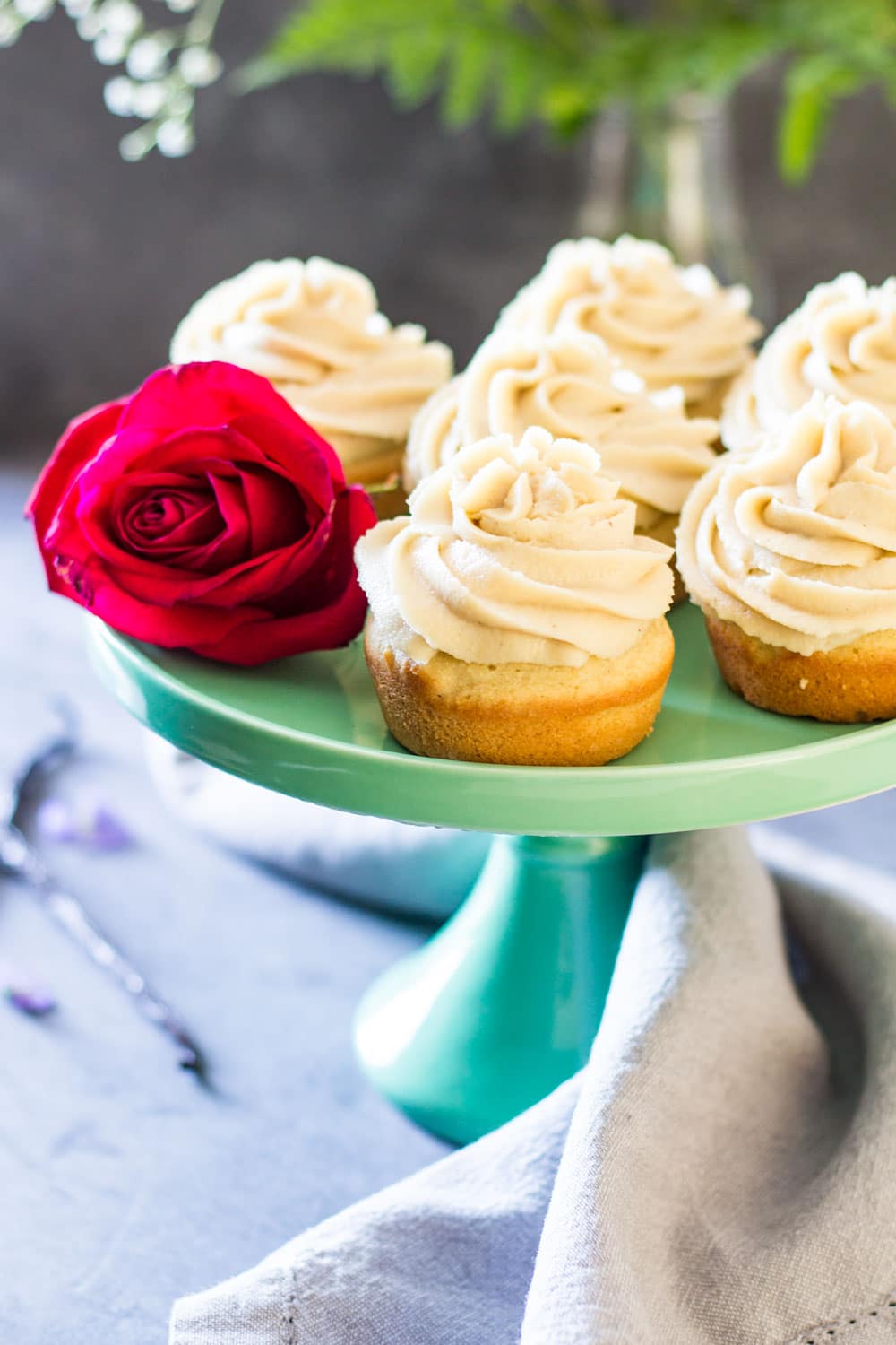 Moist Vanilla Cupcakes on a green cake stand with a rose.