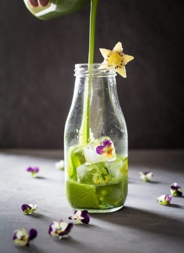 Green Smoothie being poured into a glass bottle decorated with a star-shaped kiwi slice.