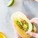 Hand holding a Squash Blossom Quesadilla and squeezing a lime on it.