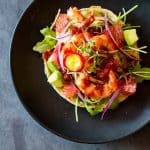 Top view of Shrimp Tostada on a black plate.