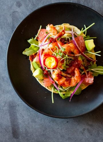 Top view of Shrimp Tostada on a black plate.