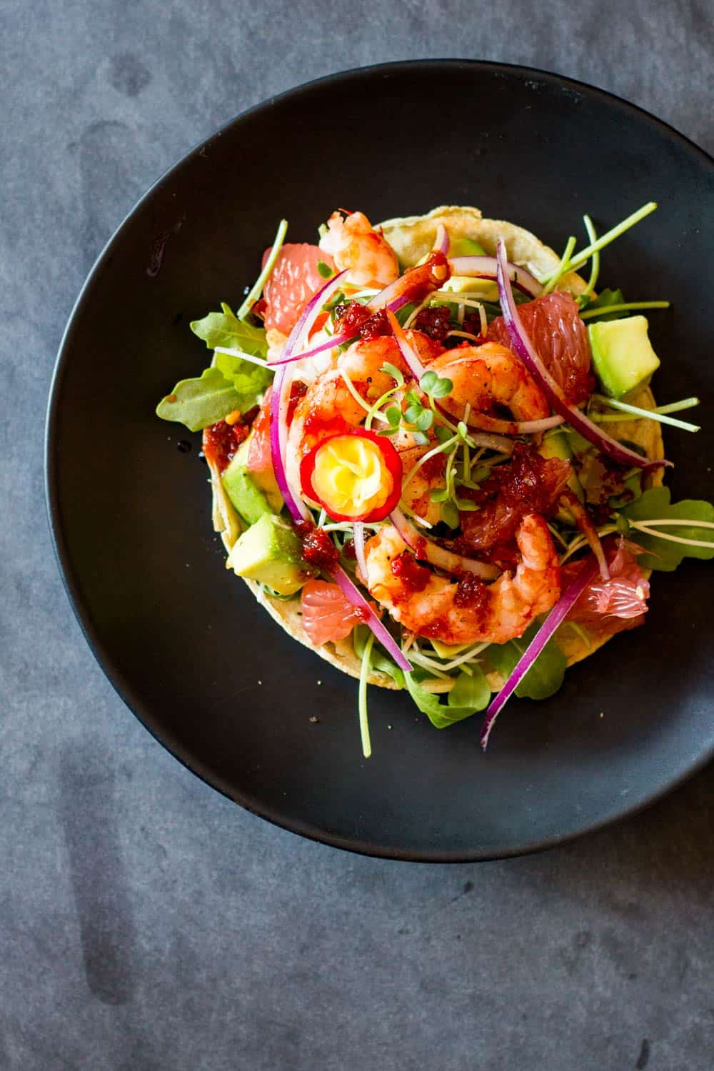 Top view of Shrimp Tostada on a black plate.