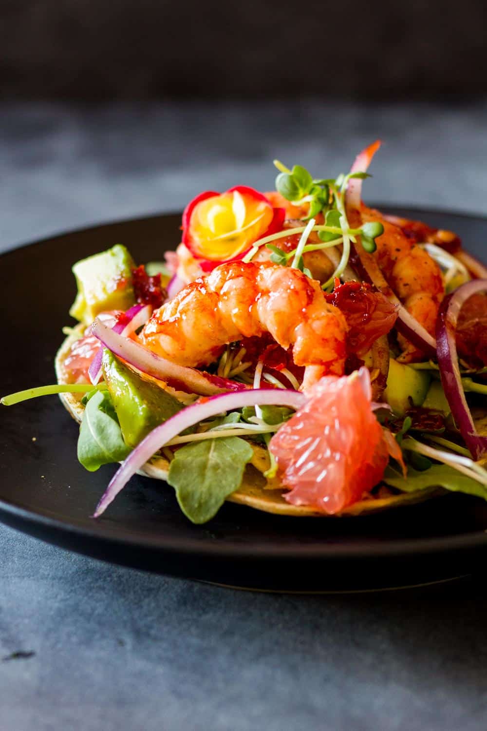 Close up of Shrimp Tostada on a black plate.