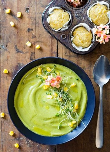 Top view of Vegan Cream Broccoli Soup, a spoon, and cornbread muffins in a muffin tin.