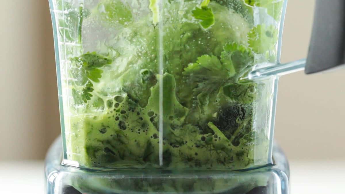 Detail of blender with cilantro, avocado and tahini being mixed. 