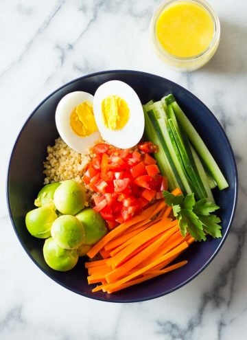 Instant Pot Quinoa Bowl with hard-boiled egg, cucumber, carrots, tomatoes, avocado and lemon tahini dressing.