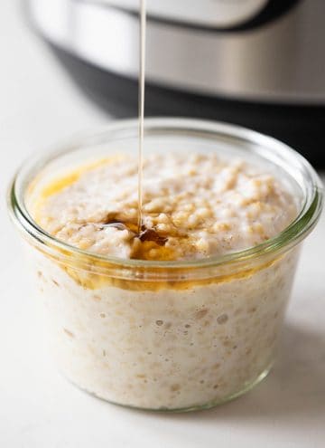 An Instant Pot in the background and cooked steel cut oats in a jar in front.