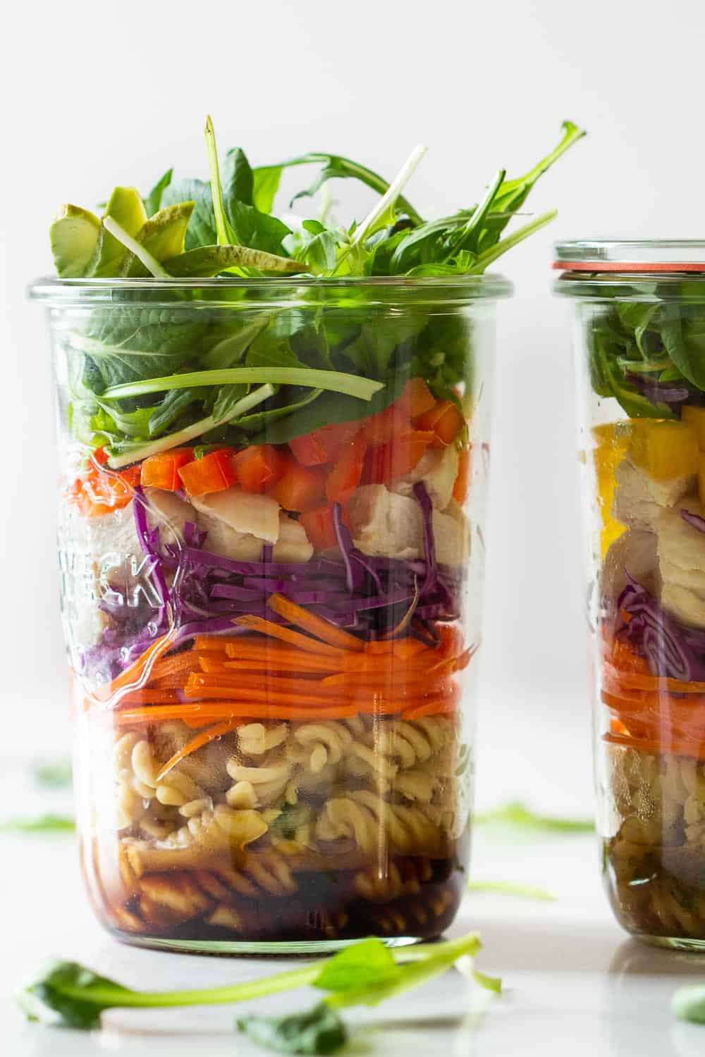 Chicken Pasta Salad in a Jar fille din layers of dressing, pasta, carrot, cabbage, bell pepper, lettuce.