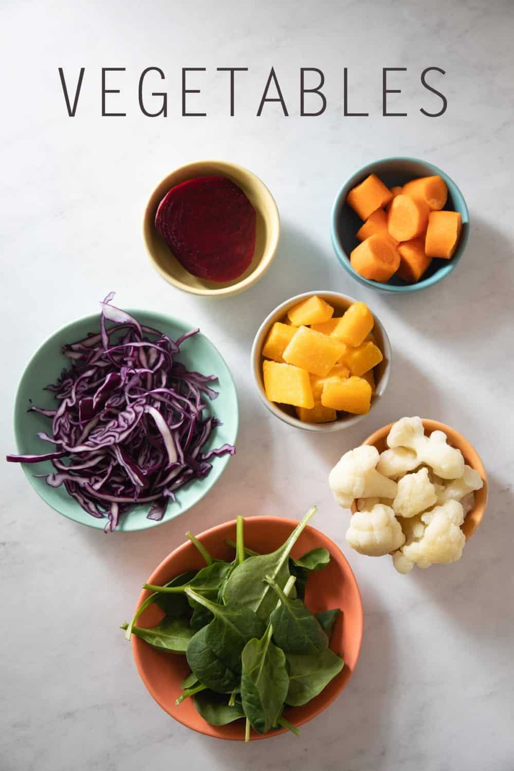 Baby Spinach, cauliflower, red cabbage, butternut squash, carrot, beet in bowls as example for best vegetables for breakfast smoothies.
