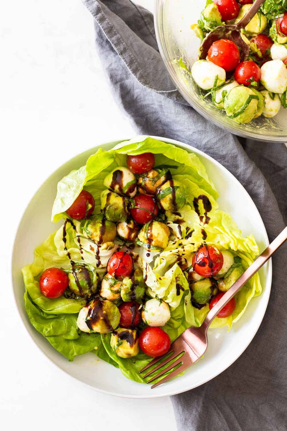 Tomato Avocado Salad served in butter lettuce leaves on a white plate.