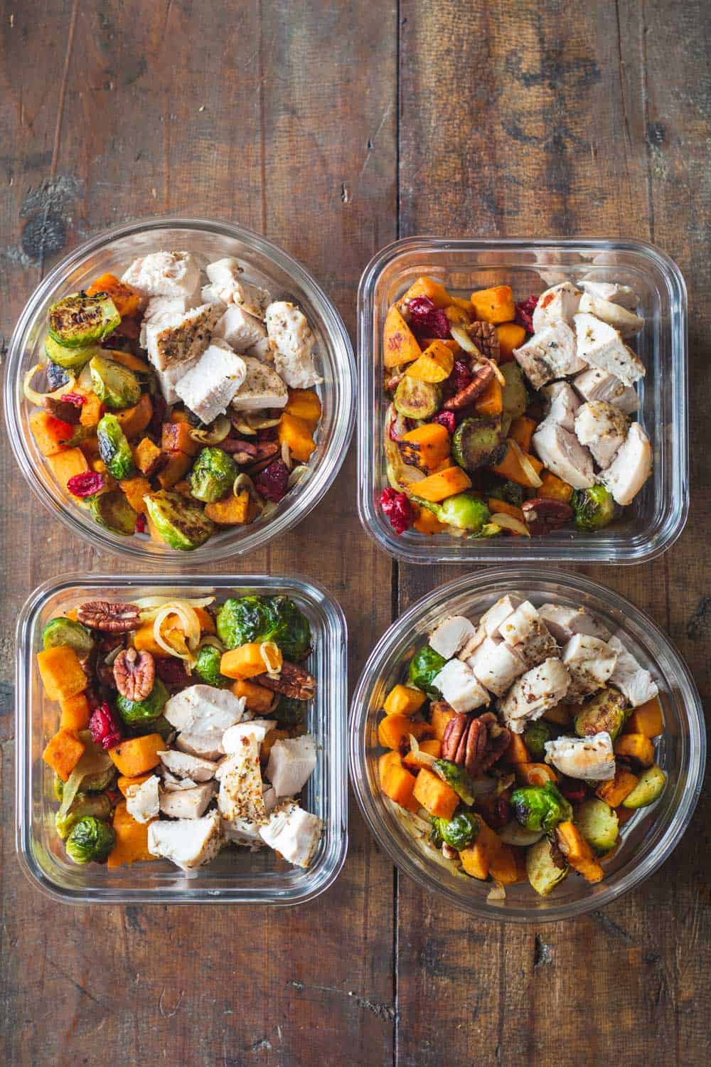 Four Maple Dijon Chicken Meal Prep Bowls on a wooden table.