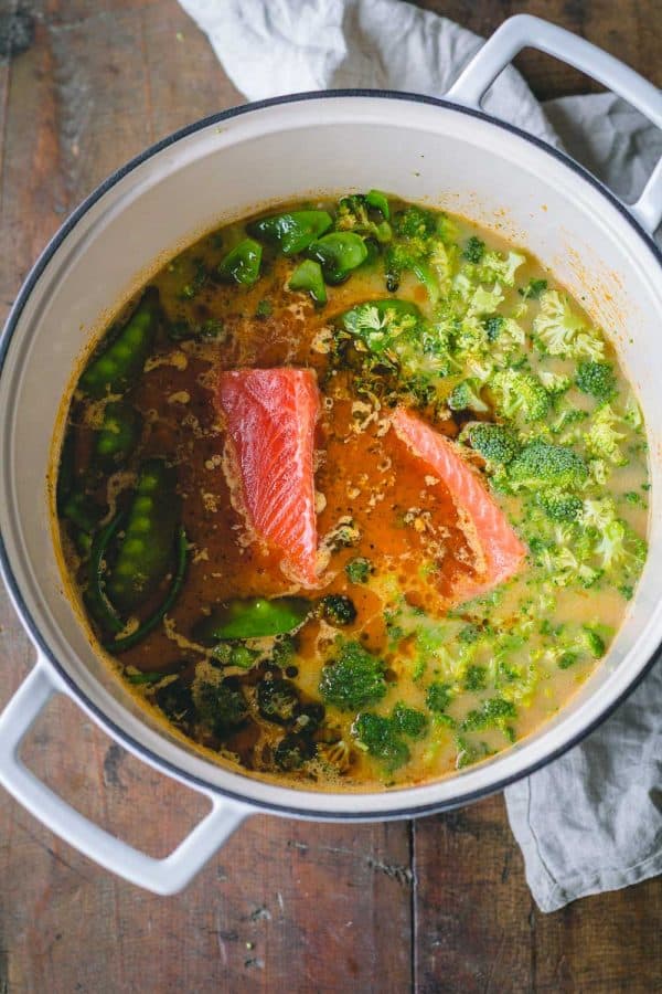 Thai Curry Soup in big white pot showing sockeye salmon fillets, potatoes, broccoli, and snow peas in broth