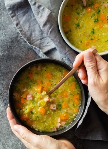 Instant Pot Split Pea Soup in two bowls and two hands holding bowl and spoon