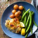Lemon Garlic Chicken Thigh on a blue plate with potatoes and green beans