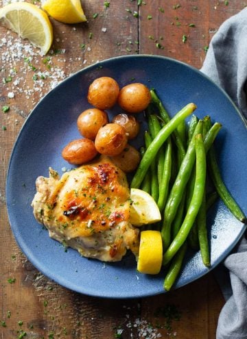 Lemon Garlic Chicken Thigh on a blue plate with potatoes and green beans