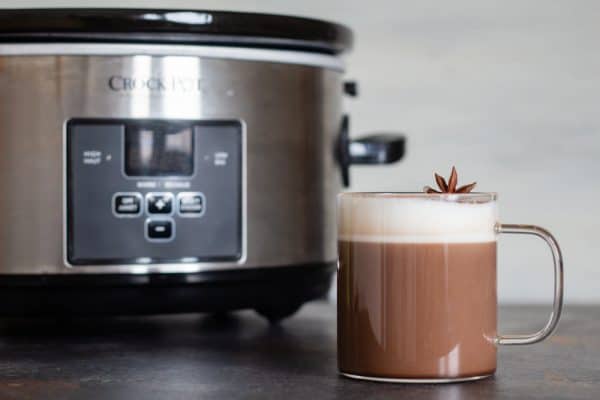 Mexican spiced hot chocolate in a cup in front of a Slow-Cooker