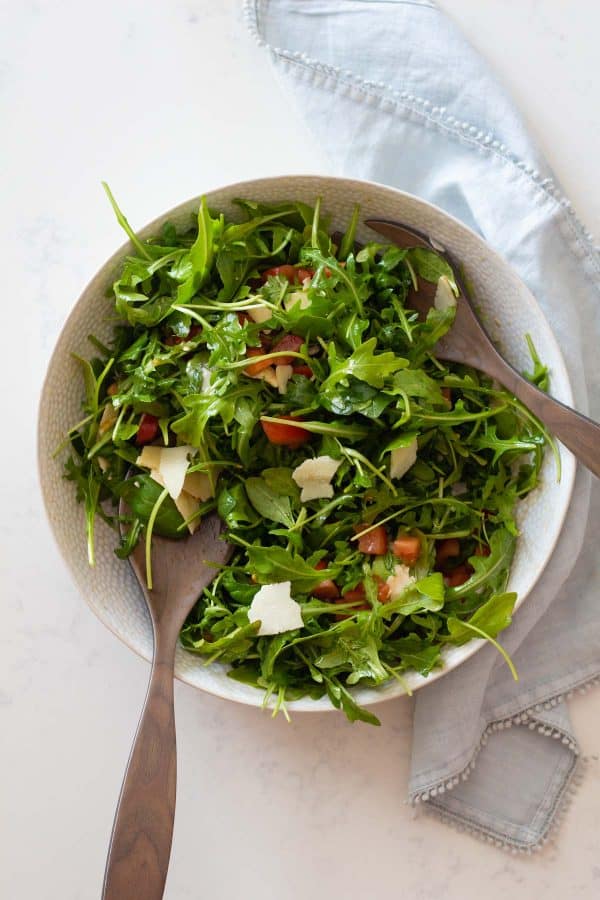 A mixed arugula salad in a white bowl