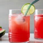 watermelon agua fresca in a glass with lime slice at edge and blue glass straw