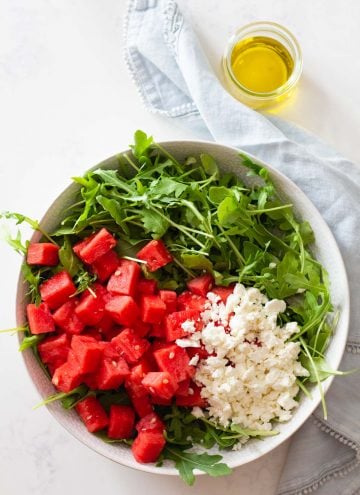 Watermelon and crumbled feta on top of arugula in a salad bowl