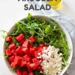arugula, watermelon, and crumbled feta in a salad bowl and text overlay for pinterest