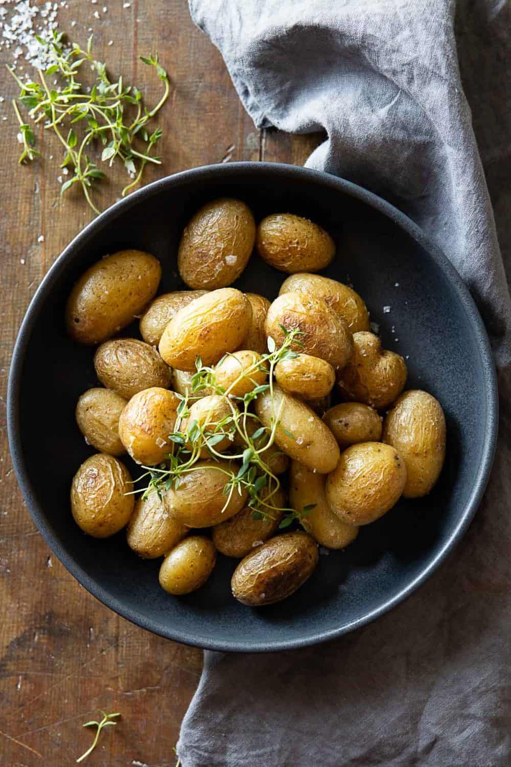 Baby Potatoes in a grey bowl garnished with fresh thyme. instant pot boiled potatoes
