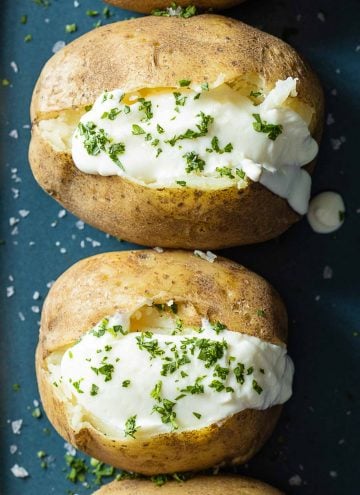 Baked Potatoes topped with sour cream and chopped parsley.