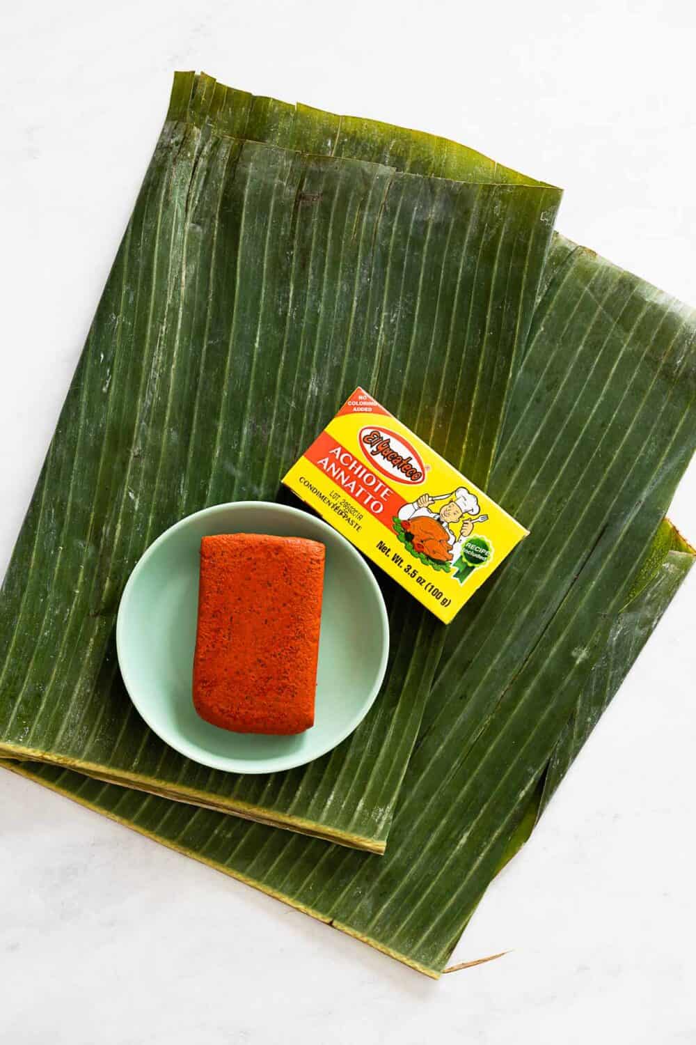 A folded banana leaf and a block of achiote paste.