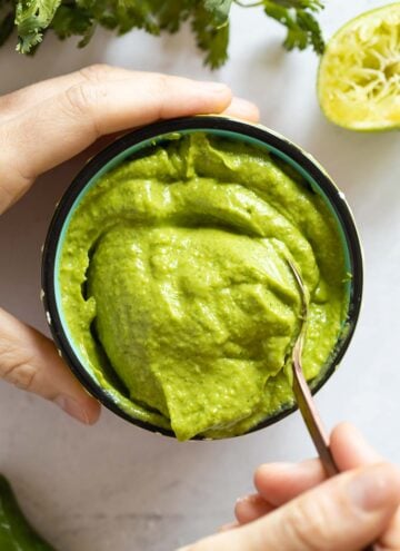 Avocado Dip in a bowl with a hand scooping out a spoon.