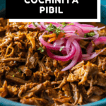 Closeup look of texture of Cochinita Pibil served in a blue bowl and topped with red onion with text overlay for Pinterest.