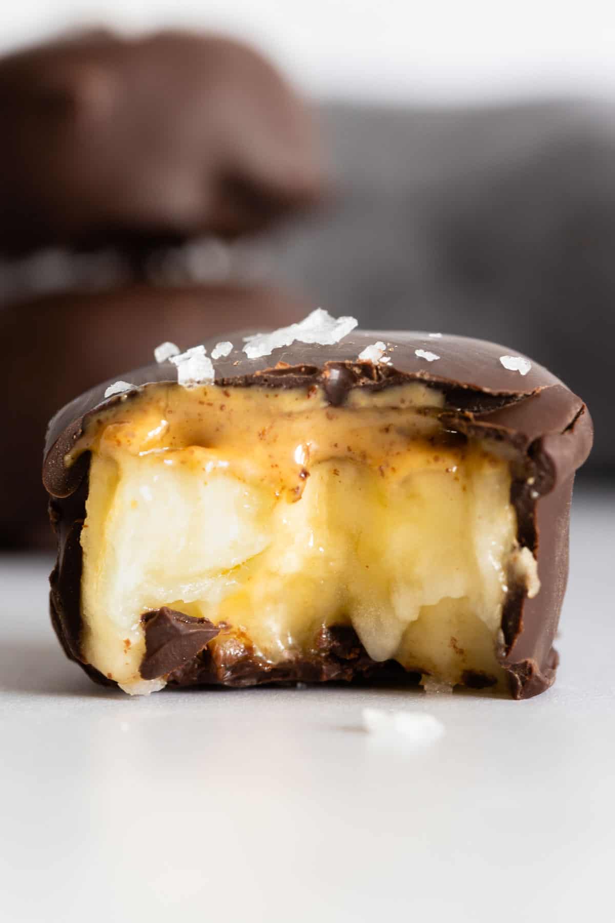 One chocolate covered banana bite bitten into to show inside texture.