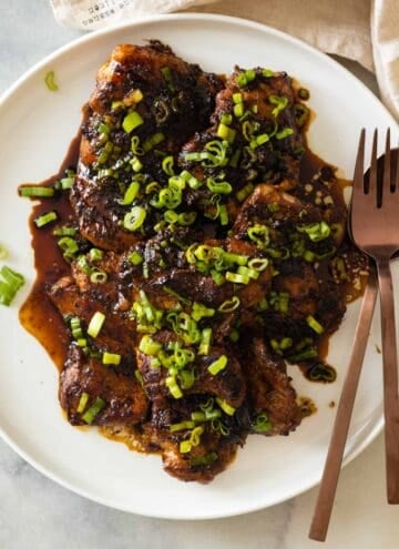 Lemongrass ginger chicken thighs on a white plate.