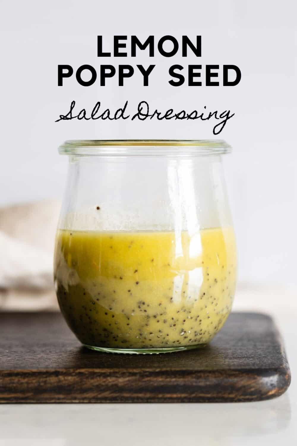 Glass jar with yellow salad dressing with title reading: Lemon Poppy Seed Salad Dressing.