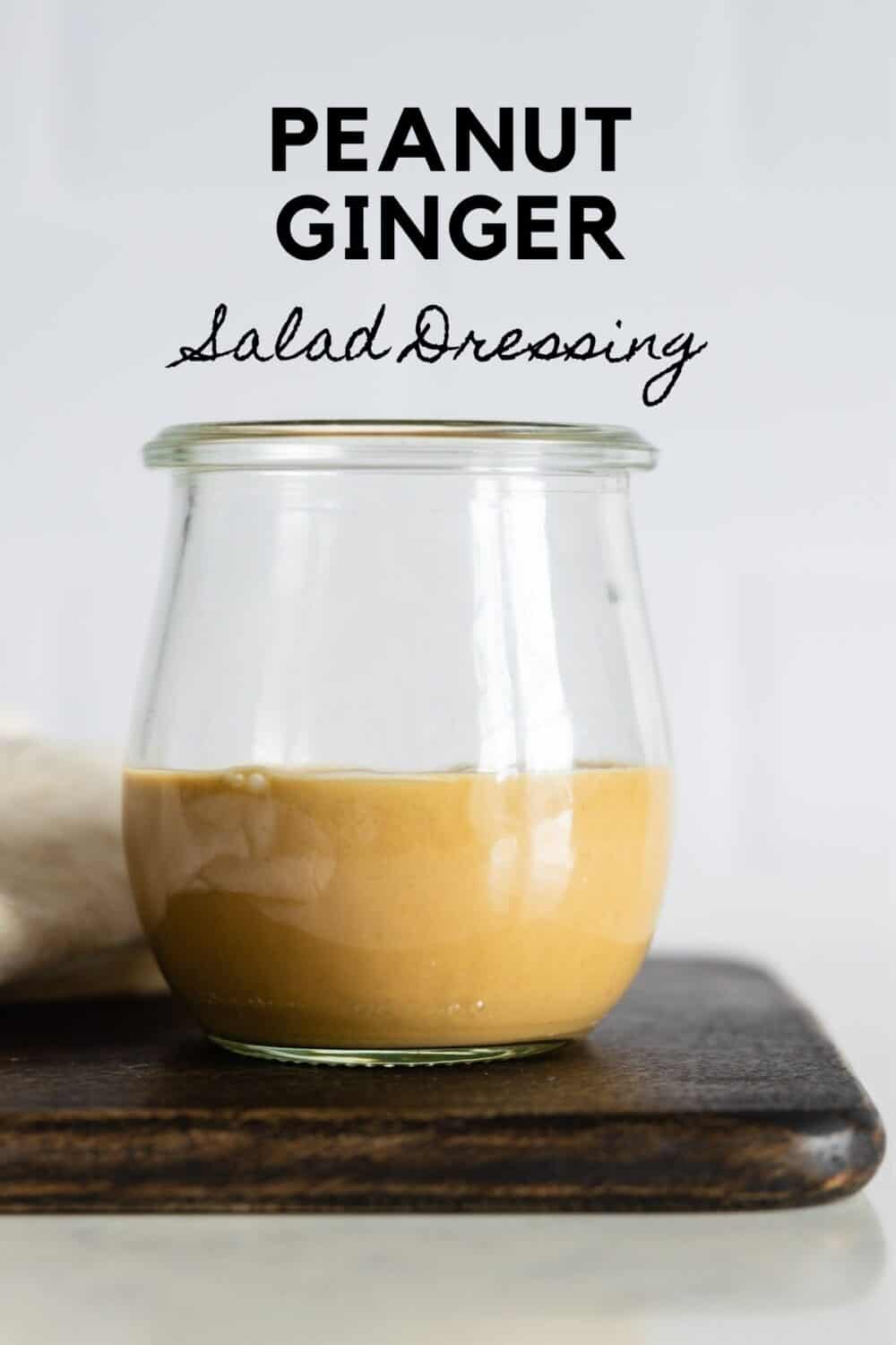 Glass jar with light brown salad dressing with title reading: Peanut Ginger Salad Dressing.