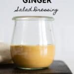 Glass jar with light brown salad dressing with title reading: Peanut Ginger Salad Dressing.