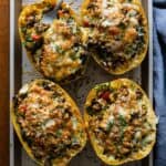4 meat stuffed spaghetti squash halves on a baking sheet.
