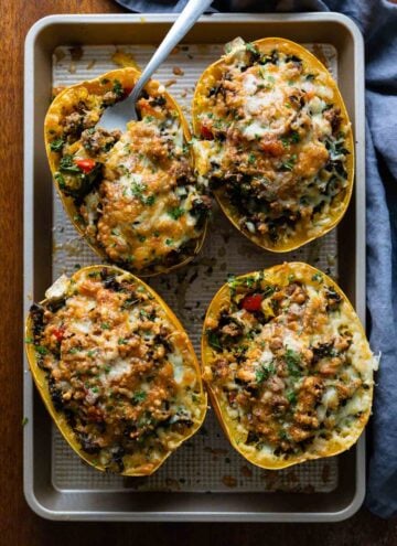 4 meat stuffed spaghetti squash halves on a baking sheet.