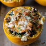 melted cheese covered, meat stuffed spaghetti squash half on a baking sheet.