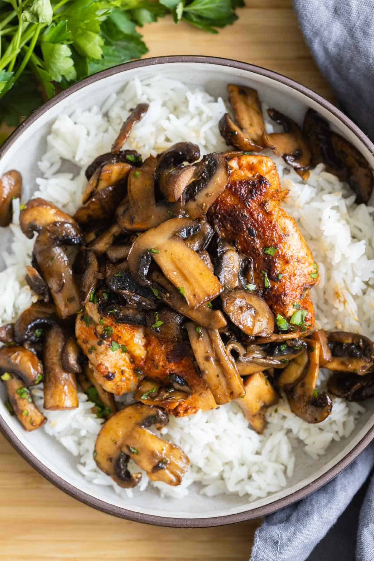 A bowl with rice, chicken, and mushrooms.