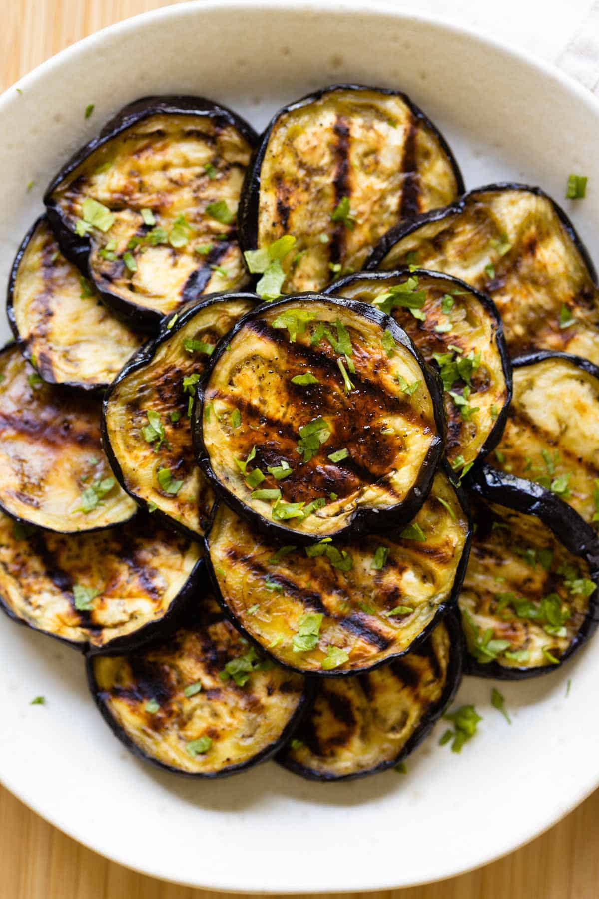 Grilled eggplant rounds stacked on a plate.