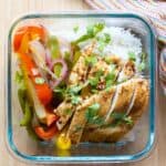 Glass meal prep container with chicken, rice, and bell peppers.